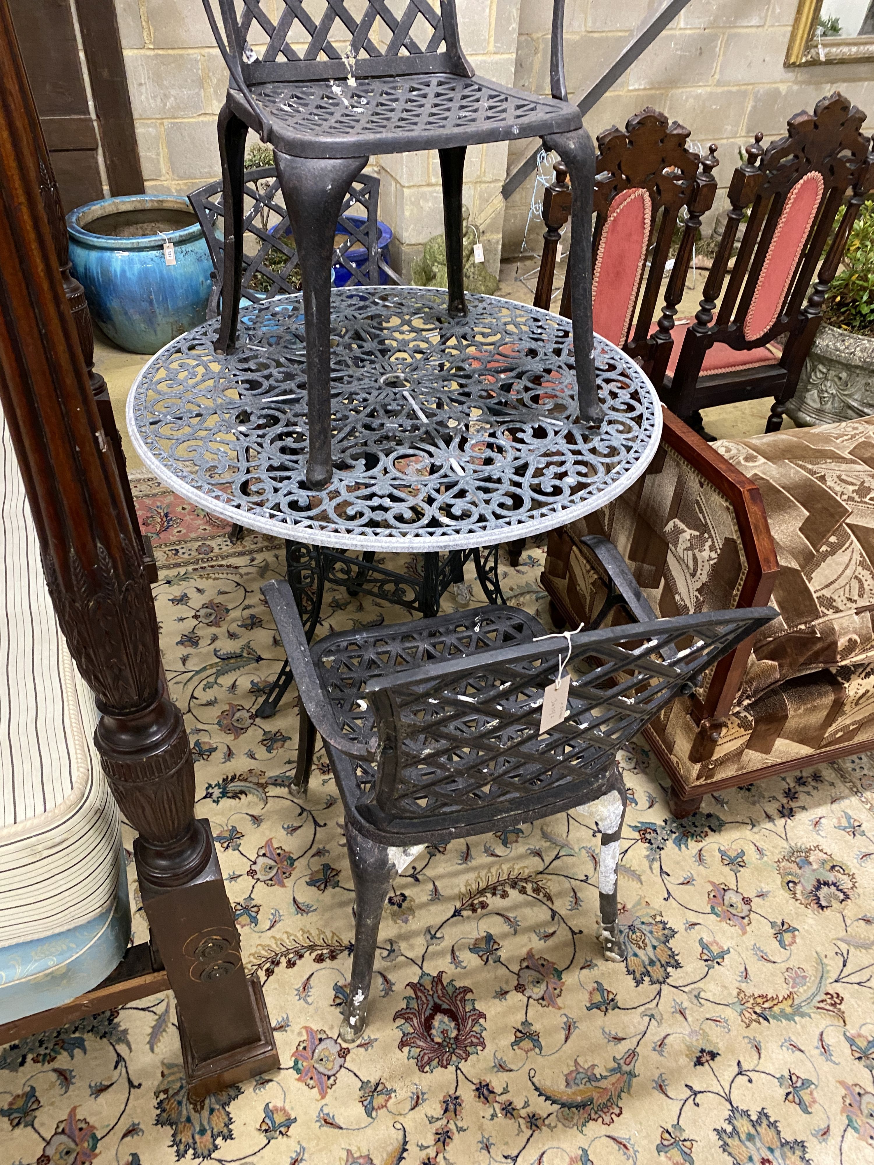 A circular painted aluminium garden table and three elbow chairs